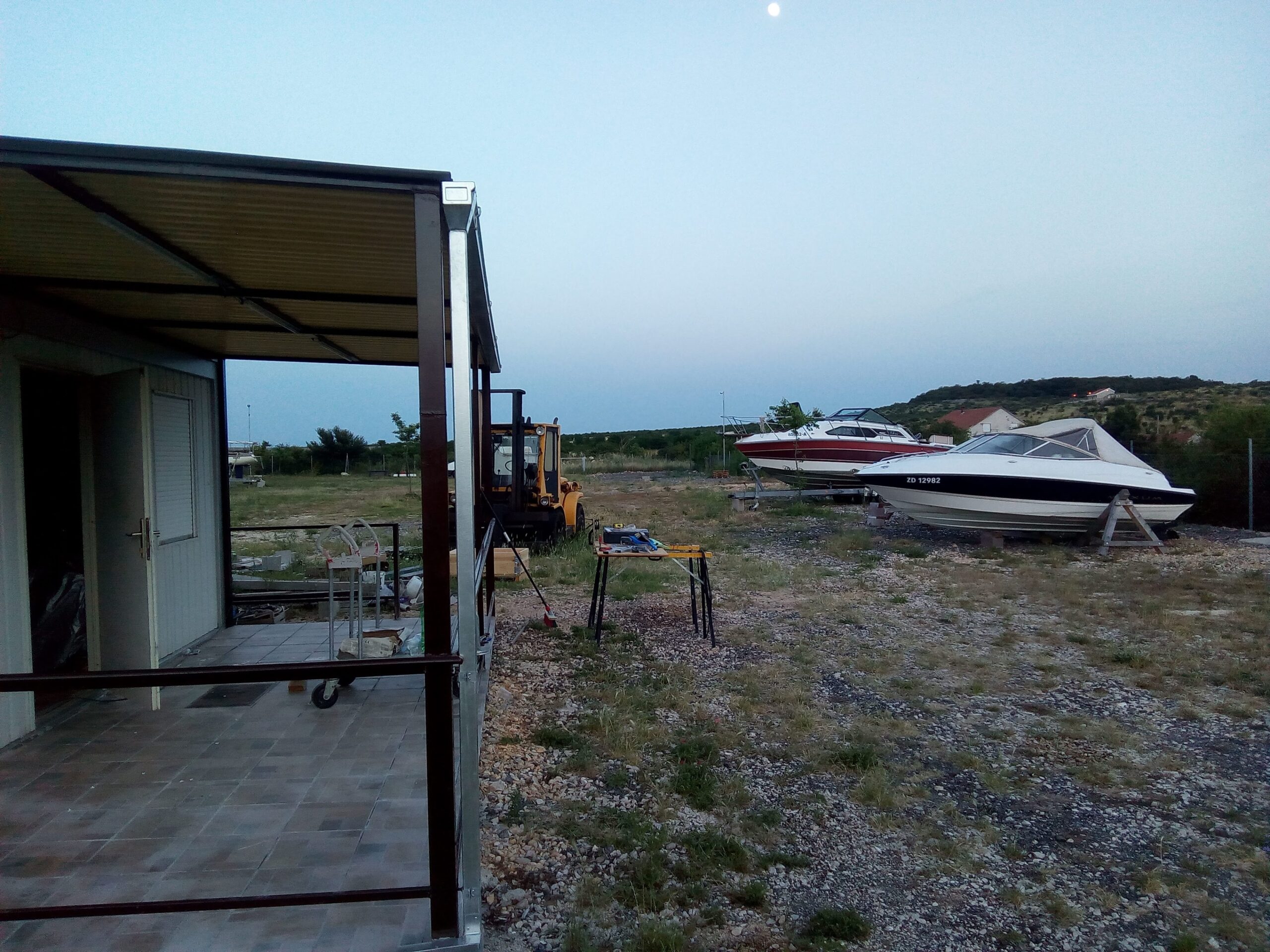 Boats stored on land in the Eurotransporti dry marina yard at evening with office container and forklift