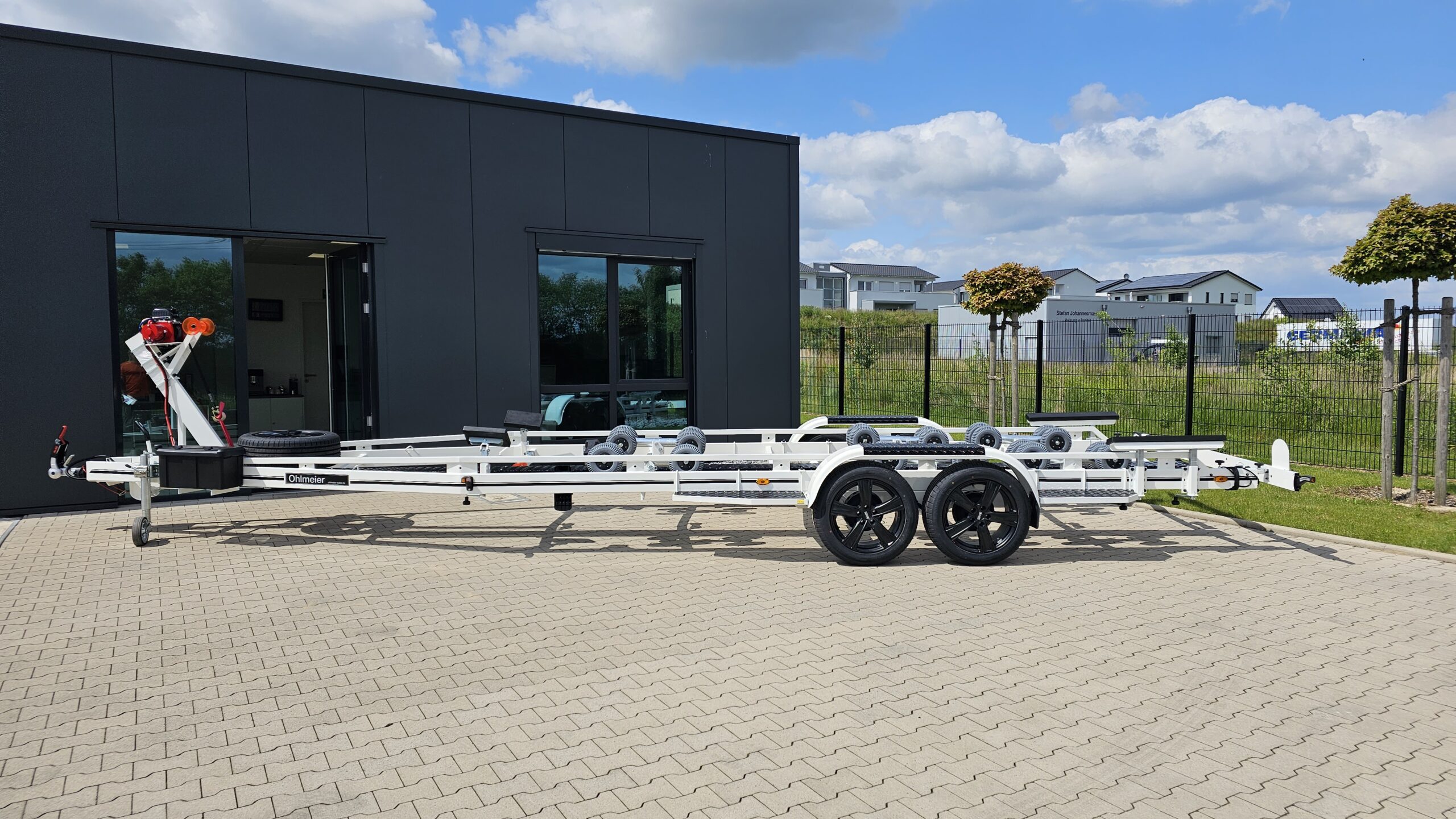 Ohmleier multi roller boat trailer parked in front of a modern building on a sunny day
