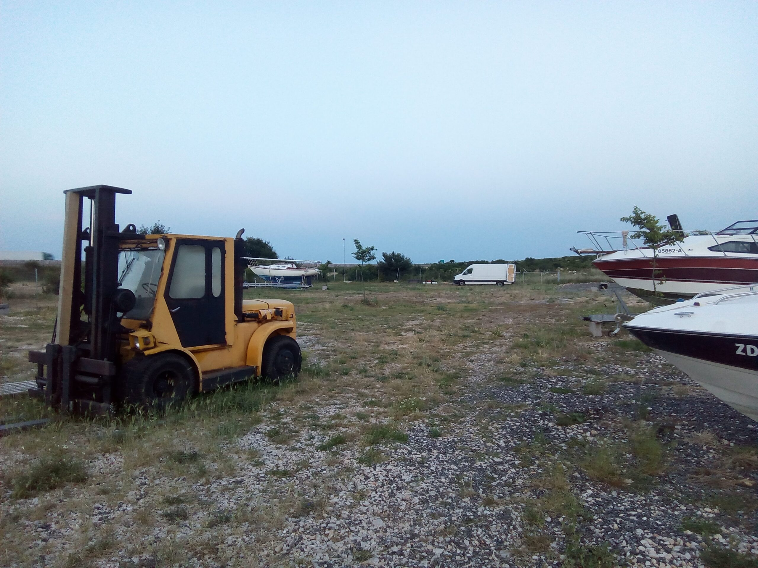 Yellow Eurotransporti forklift in boat yard with motorboats stored on land in dry marina