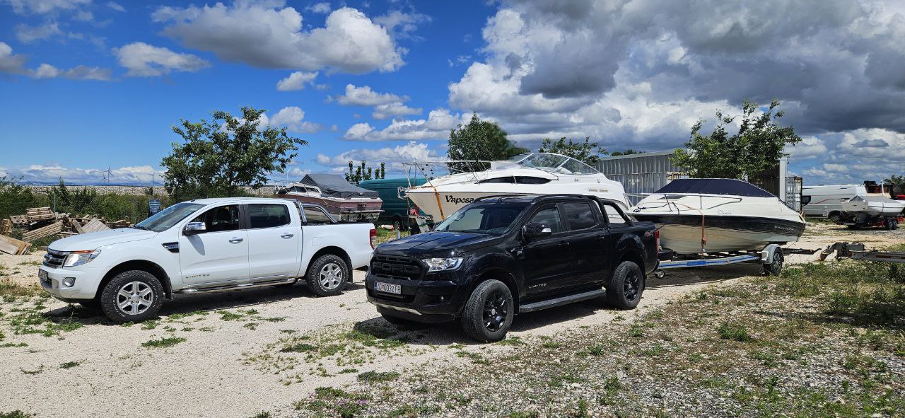 Two Ford Ranger pickup trucks towing boats on trailers during marine transport services