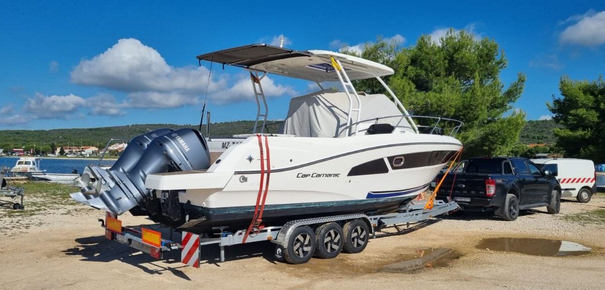 Cap Camarat Motorboot mit zwei Yamaha-Außenbordern auf einem Dreiachs-Anhänger, gezogen von einem schwarzen Ford Ranger in der Nähe des Yachthafens