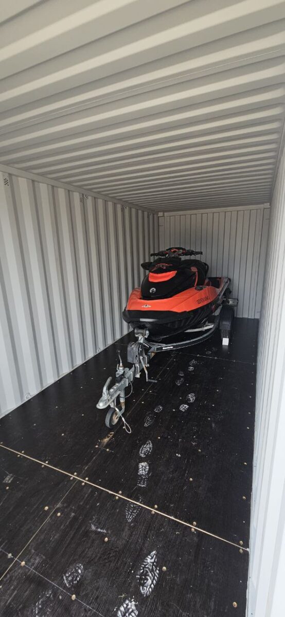 Red and black jet ski on a trailer stored inside a clean shipping container
